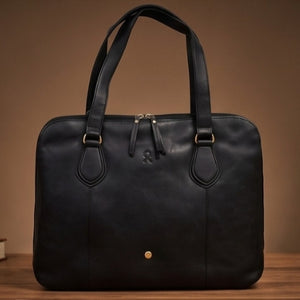 Black leather handbag on a wooden surface with a brown background