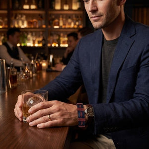 KANDM PARSE LEATHER SHOP handmade navy blue and burgundy braided leather bracelet worn by a man in a bar.