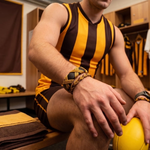 Dark brown and gold bracelet on a wooden surface with text about craftsmanship and style.Handmade leather bracelet with jute weave on a beach setting, featuring text about product features. footy,HAWTHORN HAWKS,football,club,AFL,
#AFL #Footy #AustralianRulesFootball #AFLBracelets #HandmadeJewelry #FootyFans
